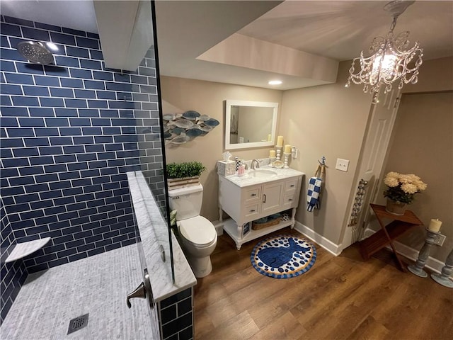 bathroom featuring vanity, toilet, wood finished floors, and tiled shower