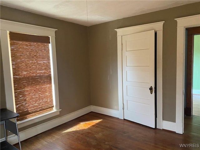 unfurnished bedroom with baseboards and dark wood-style flooring