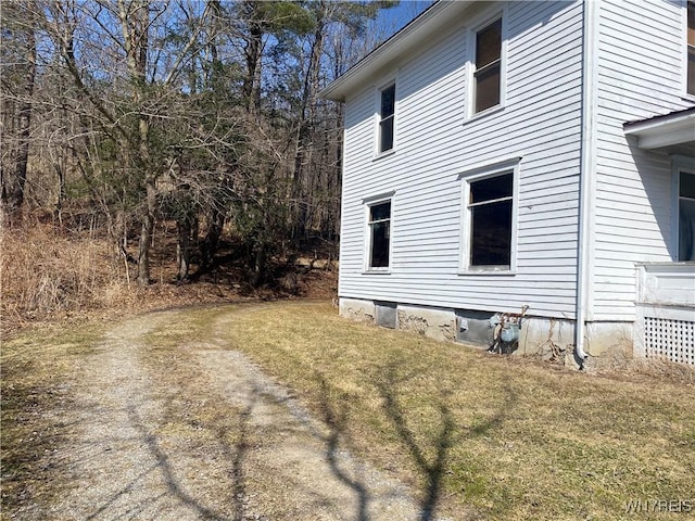 view of property exterior with a yard and dirt driveway