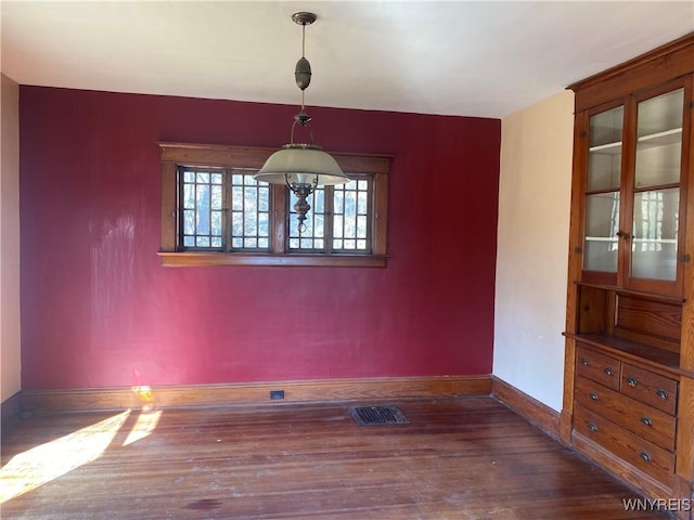 unfurnished room with visible vents, baseboards, and wood finished floors