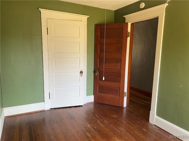 unfurnished bedroom with dark wood finished floors and baseboards