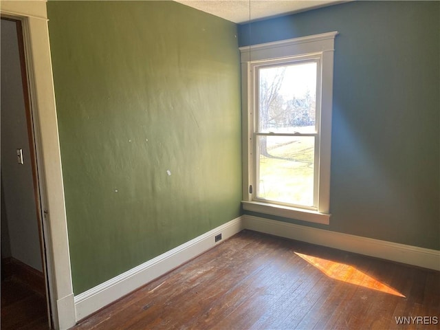 empty room with baseboards and hardwood / wood-style floors