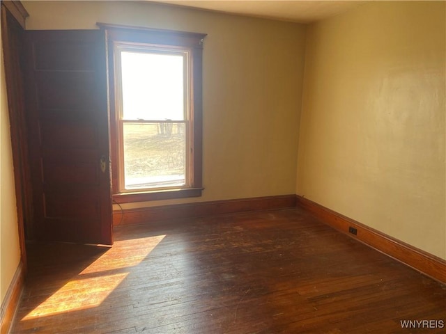 spare room featuring hardwood / wood-style floors and baseboards