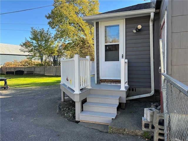 entrance to property featuring a yard and fence