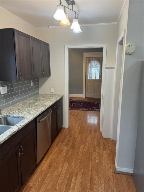 kitchen featuring ornamental molding, stainless steel dishwasher, dark brown cabinetry, light wood finished floors, and decorative backsplash