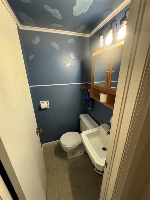 half bathroom featuring tile patterned floors, toilet, baseboards, and a sink