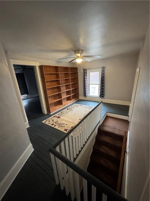 stairs with hardwood / wood-style floors, a ceiling fan, and baseboards