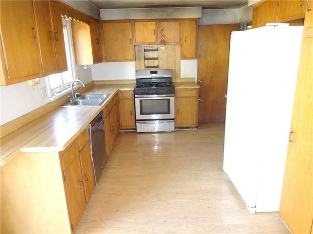 kitchen featuring a sink, stainless steel appliances, light countertops, light wood-style floors, and brown cabinets