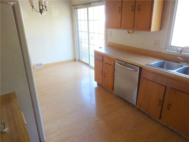 kitchen featuring visible vents, dishwasher, light wood-type flooring, a notable chandelier, and a sink