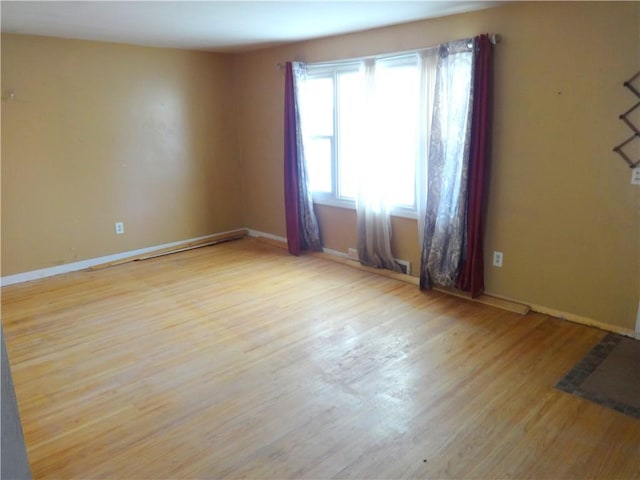 unfurnished room with baseboards and wood finished floors