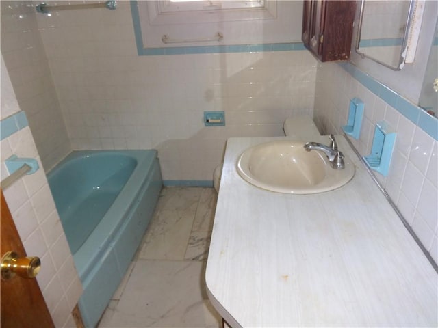 full bathroom featuring a bathing tub, marble finish floor, tile walls, and vanity