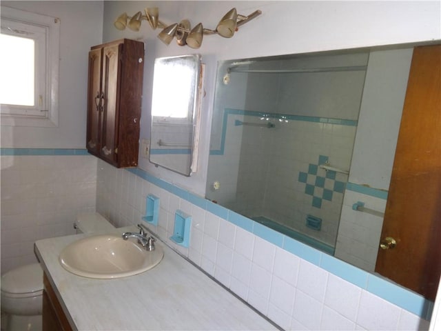 bathroom featuring tiled shower, toilet, tile walls, and vanity