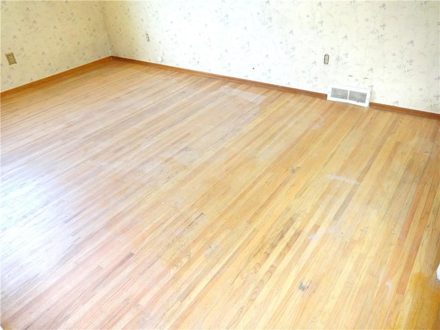 interior space featuring visible vents, baseboards, wood finished floors, and wallpapered walls