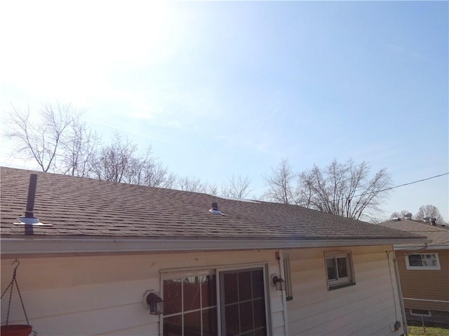 rear view of property featuring a shingled roof and fence