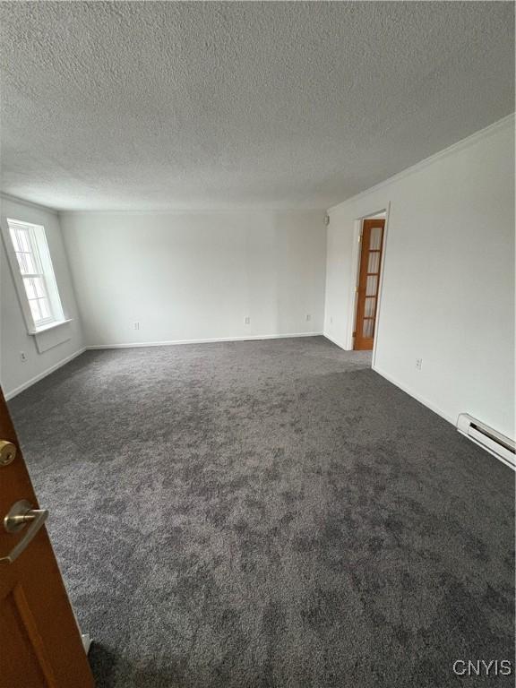 spare room with a textured ceiling, baseboards, dark colored carpet, and a baseboard radiator