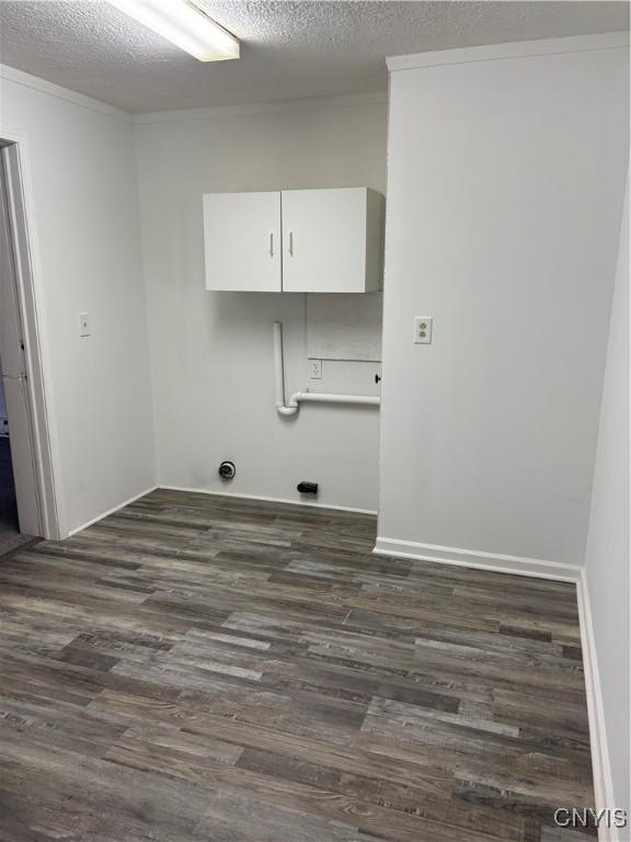 clothes washing area featuring dark wood-type flooring, cabinet space, baseboards, and a textured ceiling