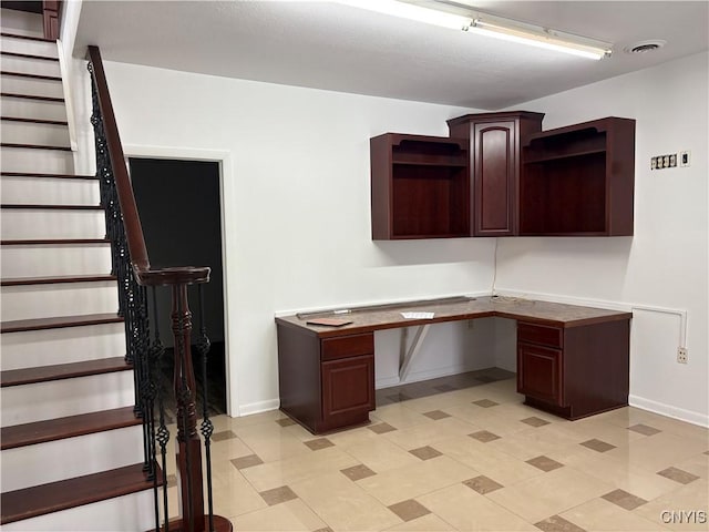 unfurnished office featuring built in desk, visible vents, and baseboards