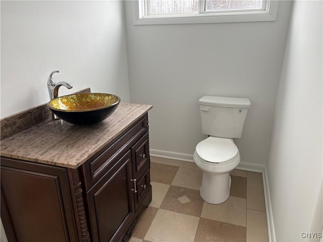 half bath featuring vanity, toilet, and baseboards