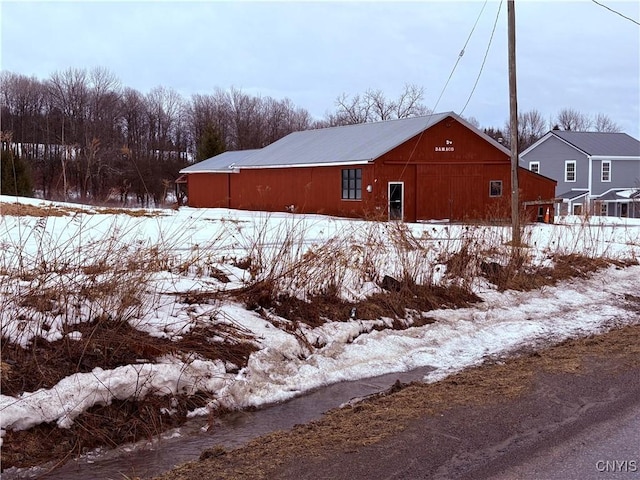 view of snow covered exterior featuring an outdoor structure and a pole building