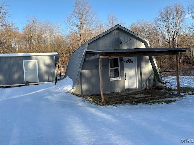 exterior space with an outbuilding, a gambrel roof, and fence