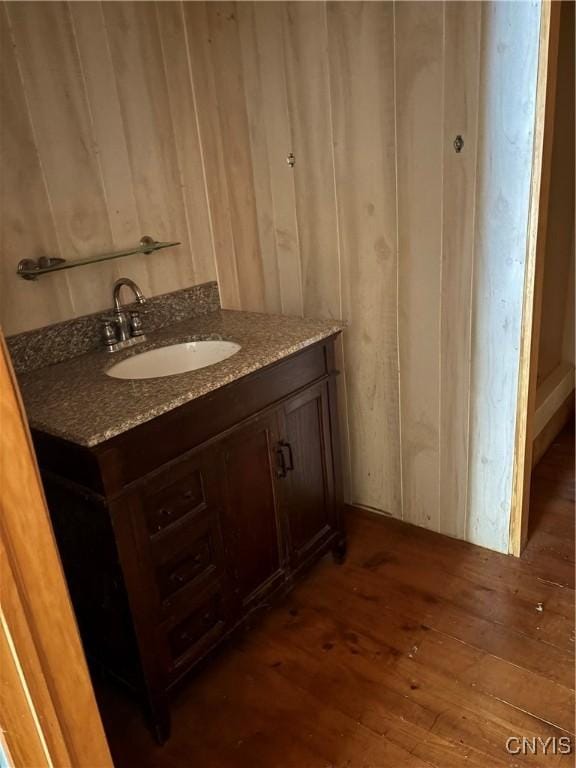 bathroom with wooden walls, hardwood / wood-style floors, and vanity