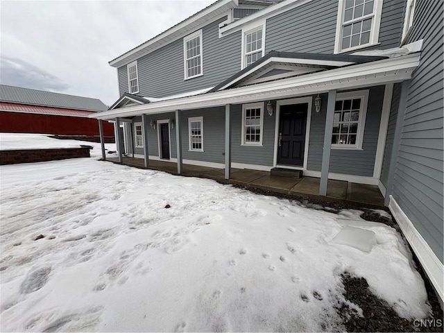 snow covered property entrance with a porch