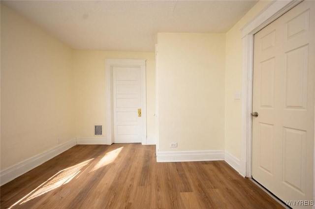 unfurnished room with visible vents, baseboards, and wood finished floors