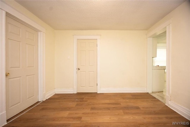 spare room featuring baseboards, a textured ceiling, and wood finished floors