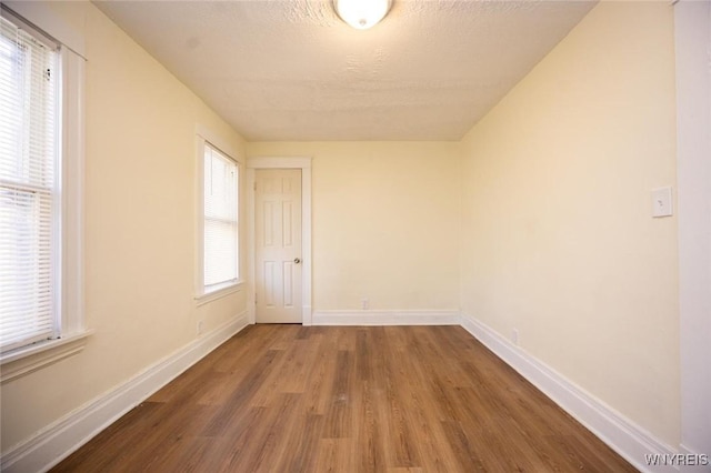 spare room featuring wood finished floors, baseboards, and a textured ceiling