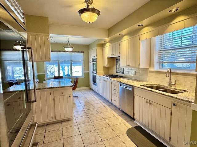 kitchen with a sink, stainless steel appliances, tasteful backsplash, and a wealth of natural light