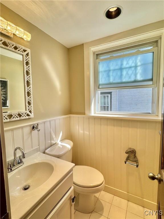 bathroom featuring vanity, tile patterned floors, toilet, and wainscoting