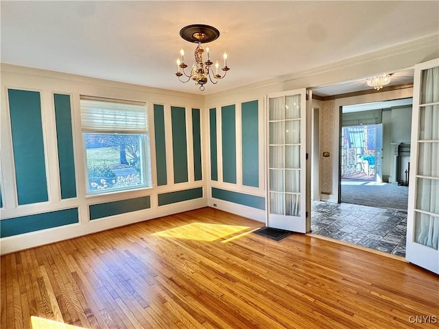 spare room with wood-type flooring and a chandelier