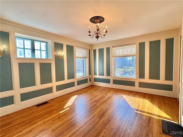 unfurnished room with a decorative wall, visible vents, and a chandelier