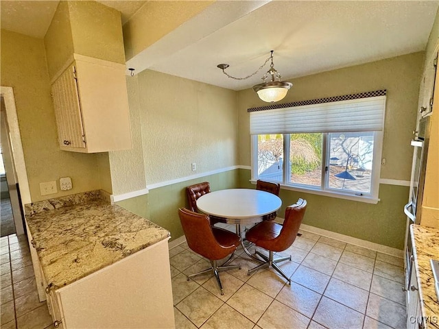 dining area with light tile patterned flooring, baseboards, and a textured wall