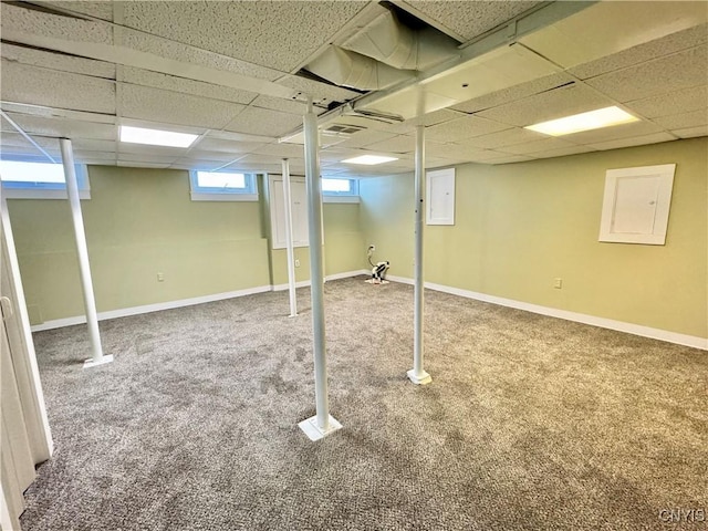 below grade area with electric panel, a paneled ceiling, baseboards, and carpet floors