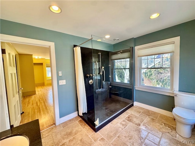 full bathroom featuring stone tile floors, toilet, baseboards, and a stall shower