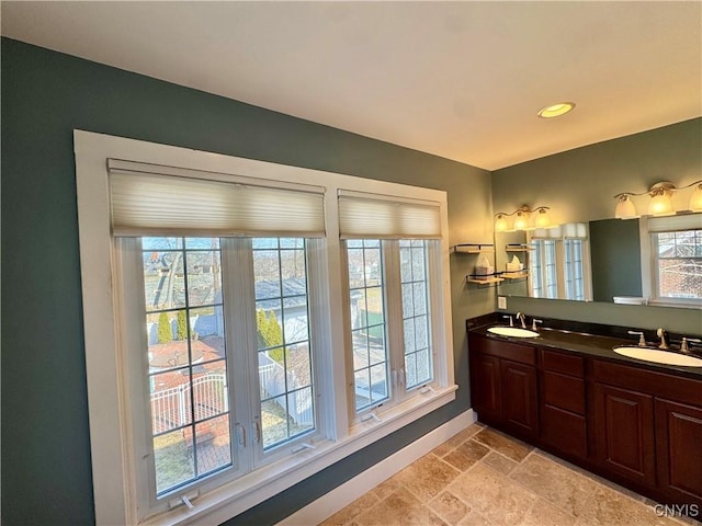 bathroom with a sink, recessed lighting, stone tile flooring, and double vanity