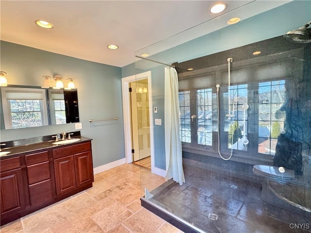 full bathroom featuring a sink, baseboards, plenty of natural light, and a walk in shower