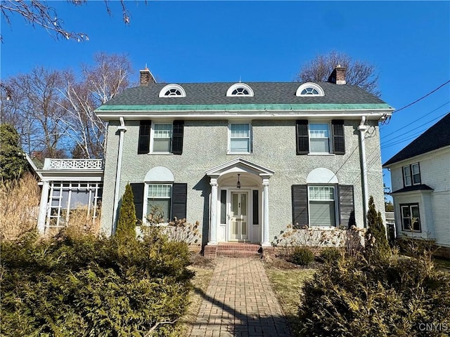 colonial inspired home with a chimney and roof with shingles