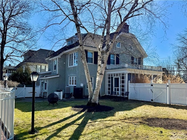 rear view of property with a gate, a fenced backyard, a sunroom, a chimney, and a lawn