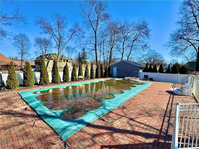 pool with a patio area, an outdoor structure, and fence