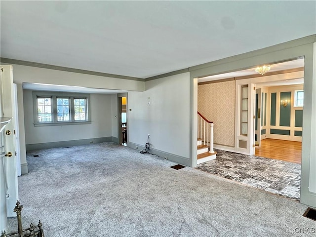 unfurnished living room with wallpapered walls, stairs, baseboards, and carpet floors