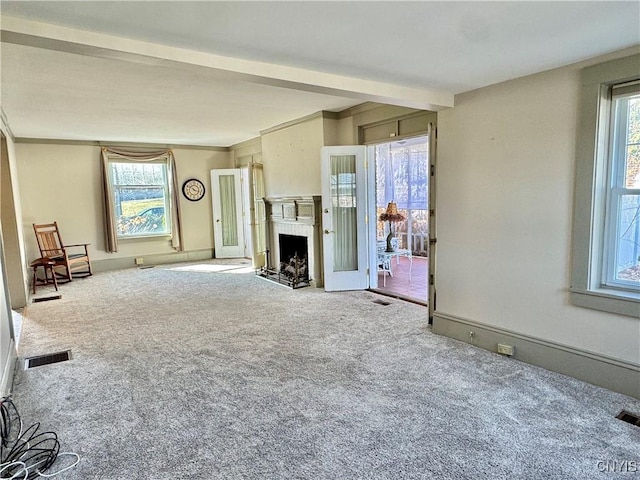 unfurnished living room with visible vents, a fireplace with flush hearth, carpet flooring, and crown molding