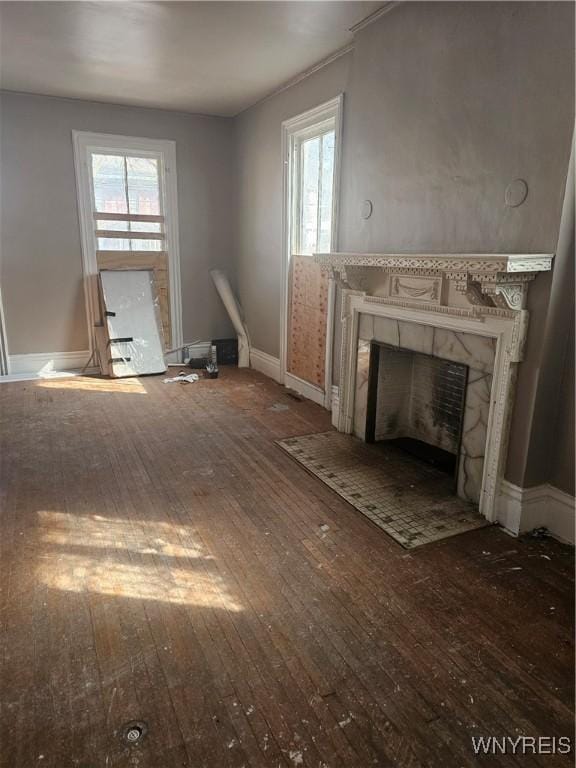 unfurnished living room featuring a high end fireplace, baseboards, and wood-type flooring