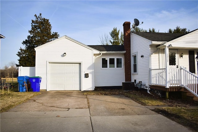 view of home's exterior with roof with shingles, an attached garage, driveway, and a chimney