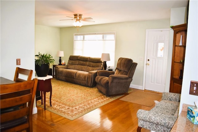 living area with baseboards, ceiling fan, and wood finished floors