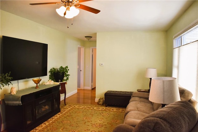 living area with wood finished floors, a fireplace, baseboards, and ceiling fan