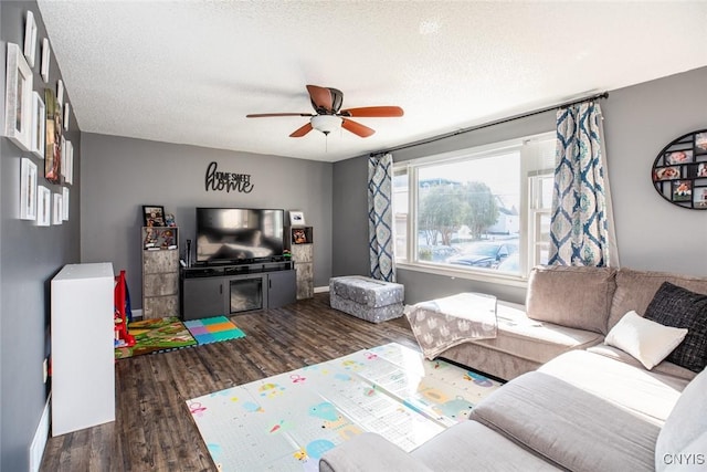 living room with ceiling fan, wood finished floors, baseboards, and a textured ceiling