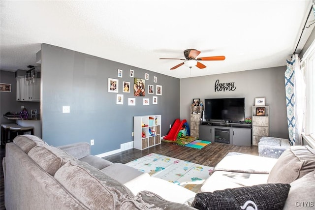 living room featuring baseboards, a ceiling fan, and wood finished floors