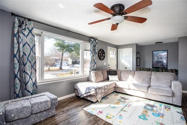 living area with ceiling fan, wood finished floors, baseboards, and a textured ceiling